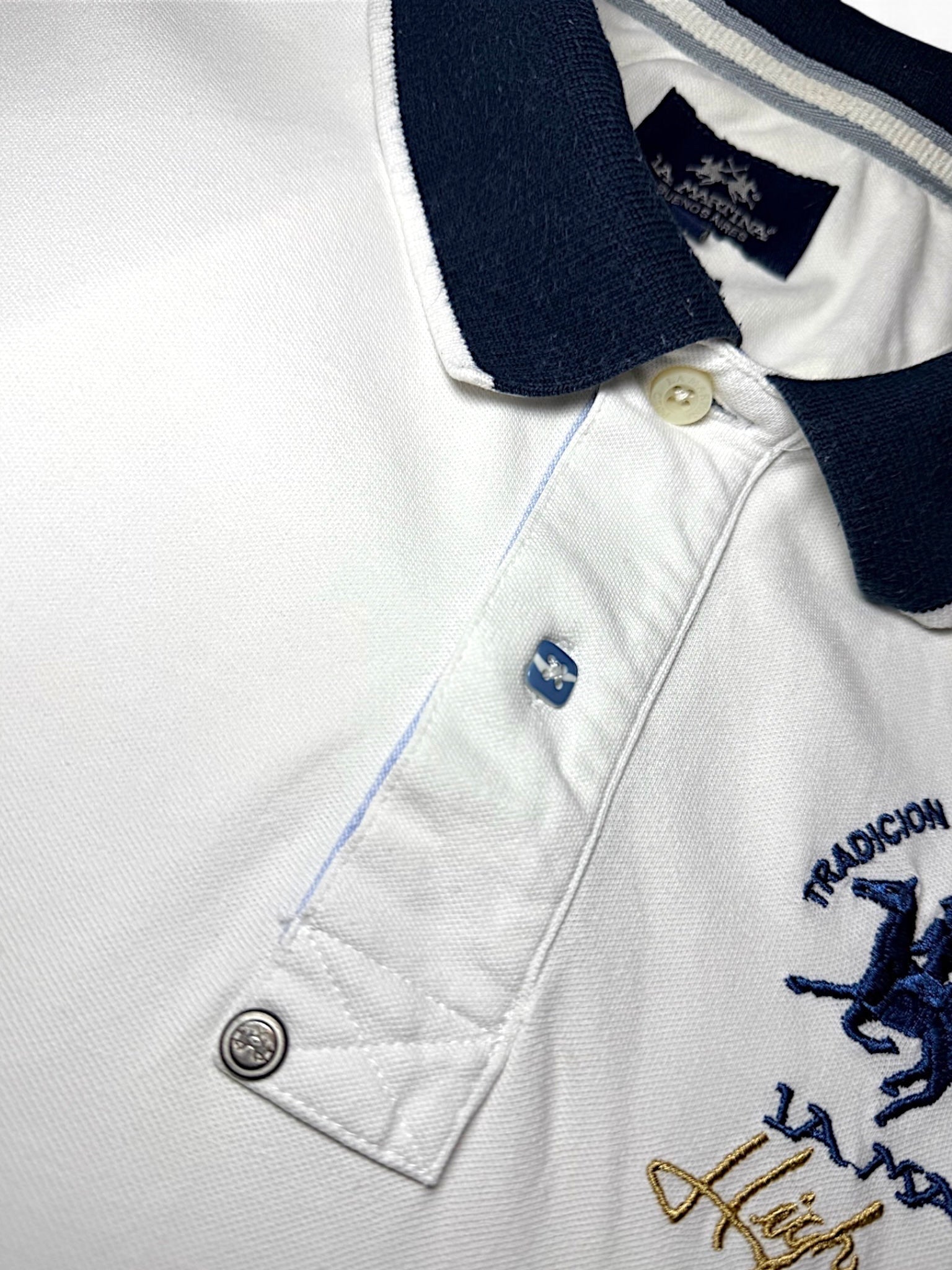 XTENDED white cotton polo shirt with navy collar and blue embroidered horse logo. Features a button placket and vintage detailing.